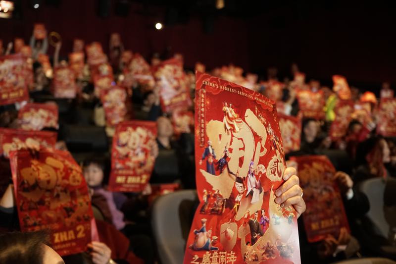 人们在美国洛杉矶举行的《哪吒之魔童闹海》北美首映礼上举起电影海报。